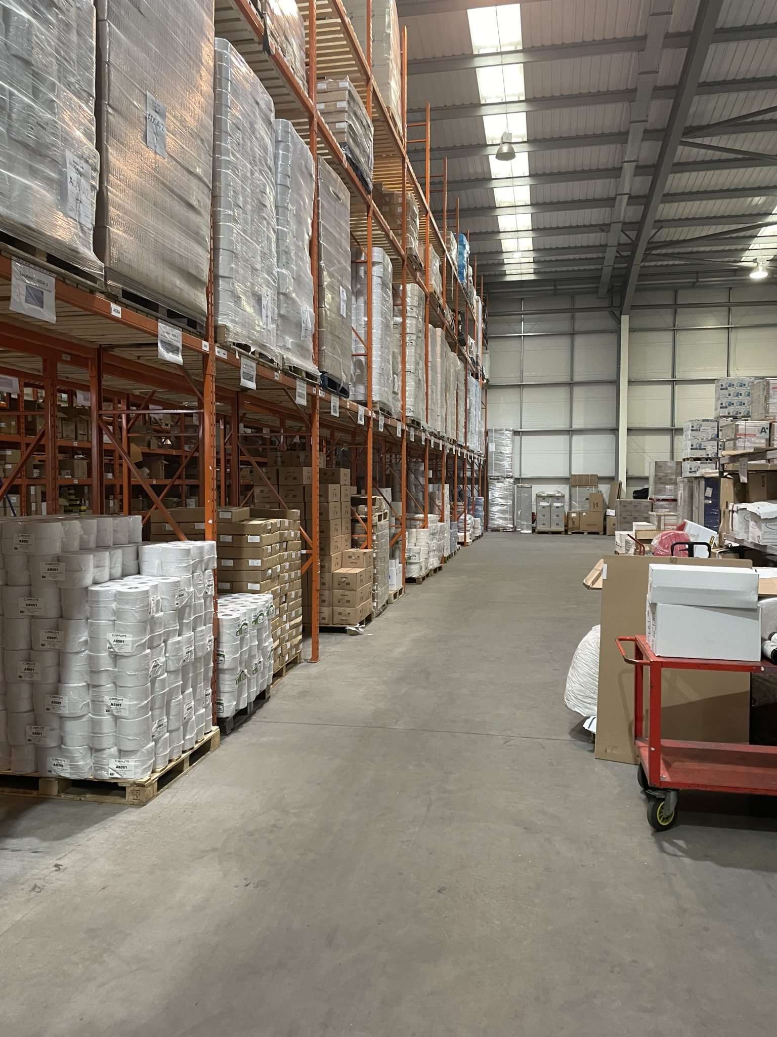 Almacén de insumos industriales con racks y tarimas para surtir bajo necesidad.